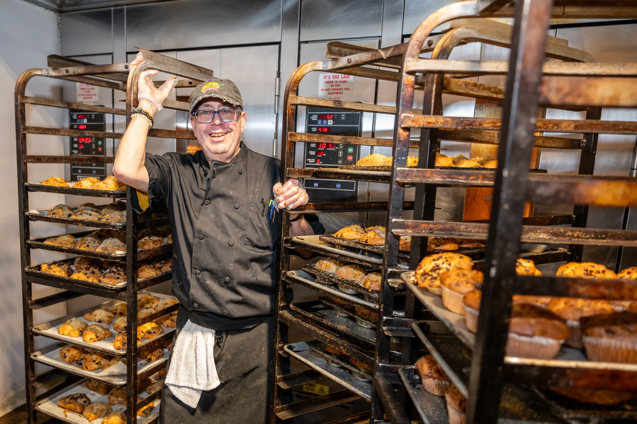 A baker at the racks of freshly baked bread and pastries