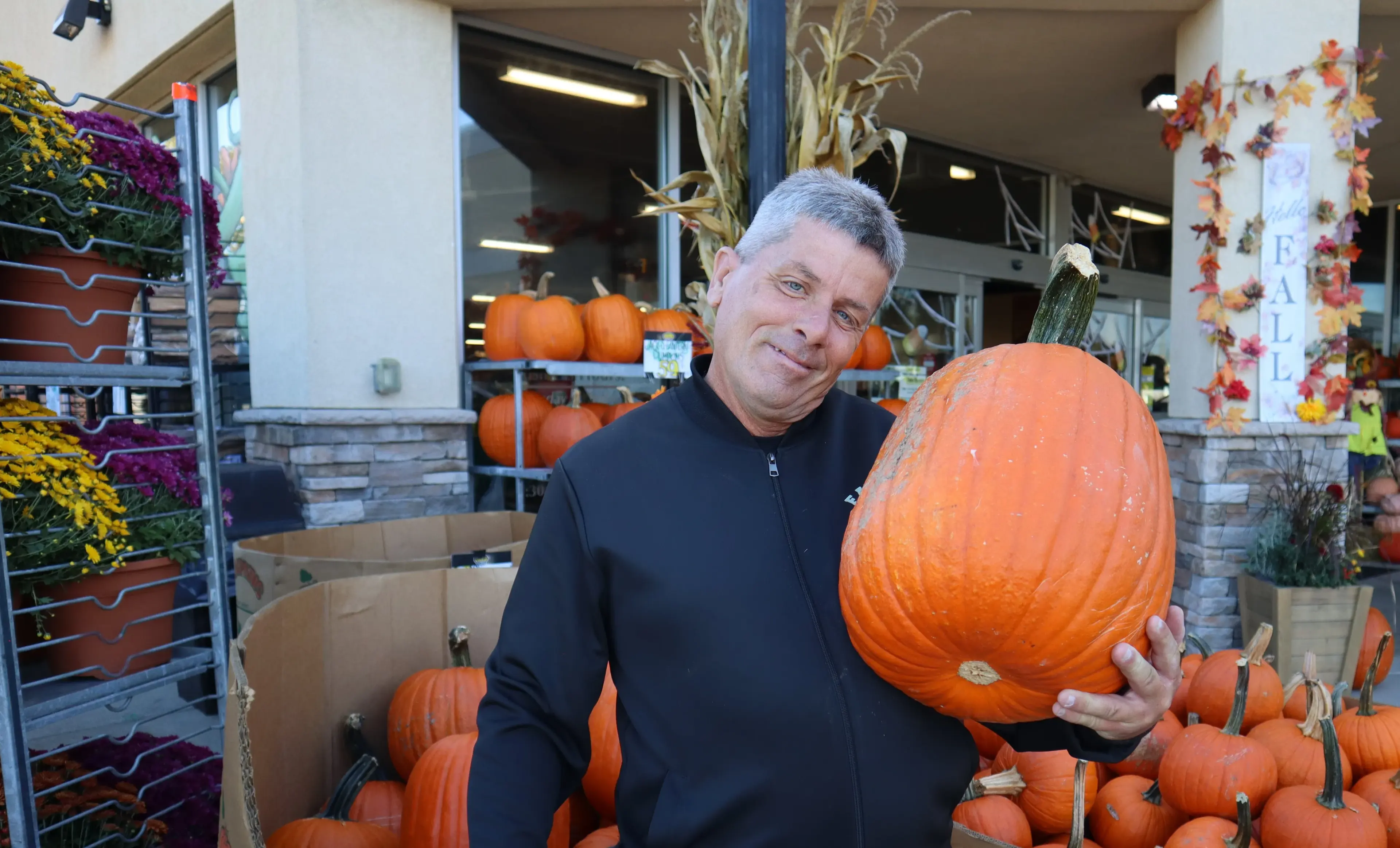 A staff member holding a pumpkin at the fall display